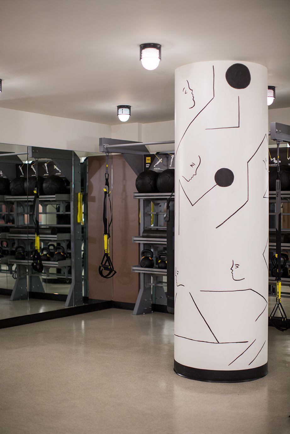 Gym interior with exercise machines and two decorated white columns with black geometric designs