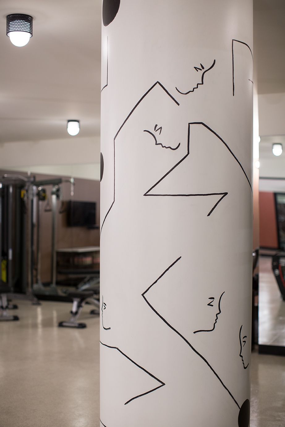 White column in gym-like hallway covered with black zigzag marker lines and notes.