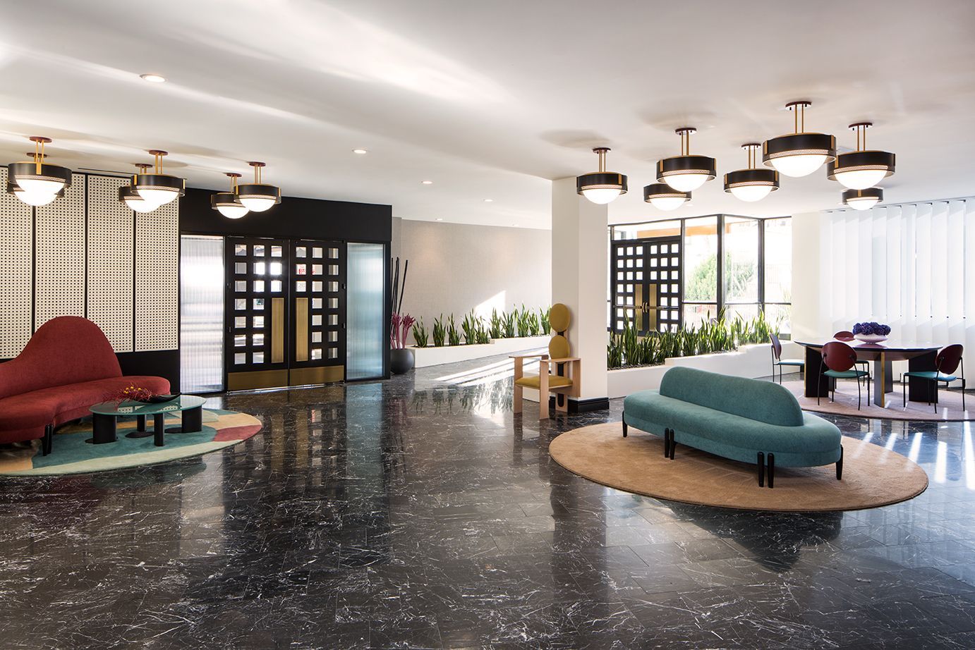 Modern hotel lobby with colorful curved sofas, round tables, and patterned black-and-white flooring