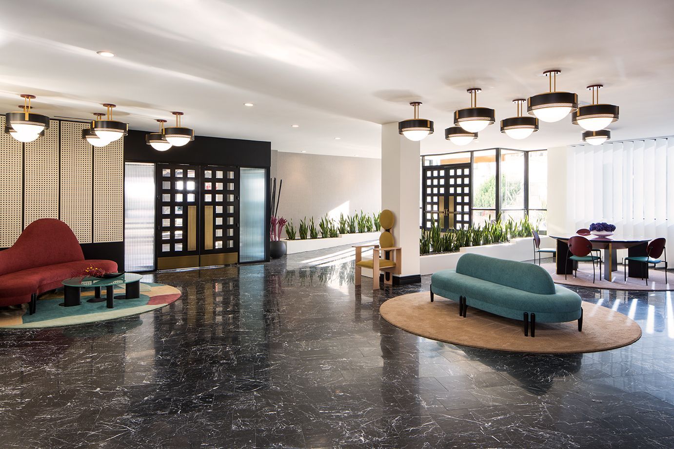 Modern hotel lobby with colorful sofas, circular chandeliers, and glossy black marble floor
