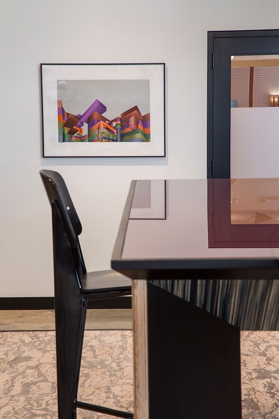 Modern dining room with a black chair, glossy table, and framed colorful artwork on the wall