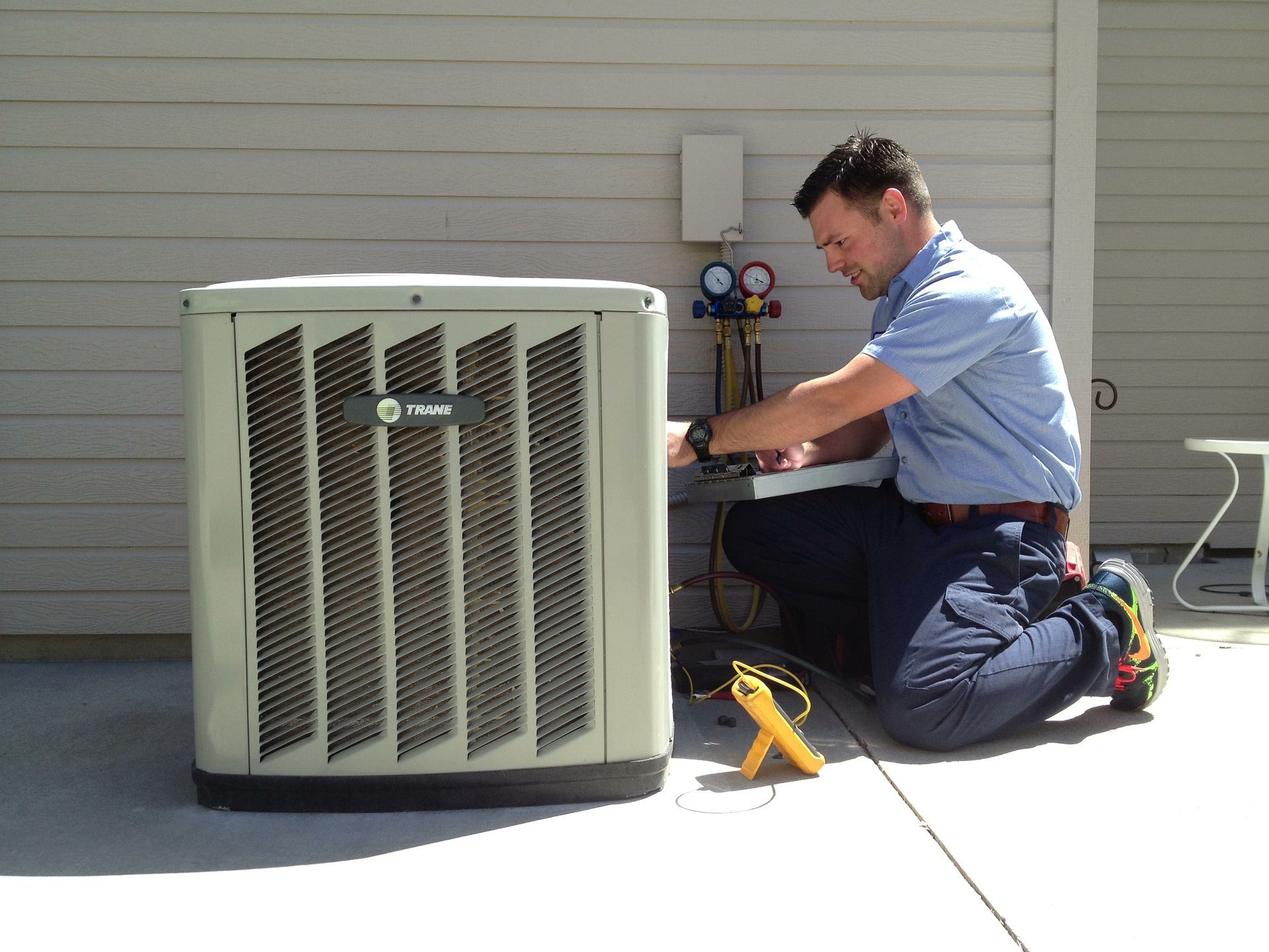 A man is working on an air conditioner outside of a house
