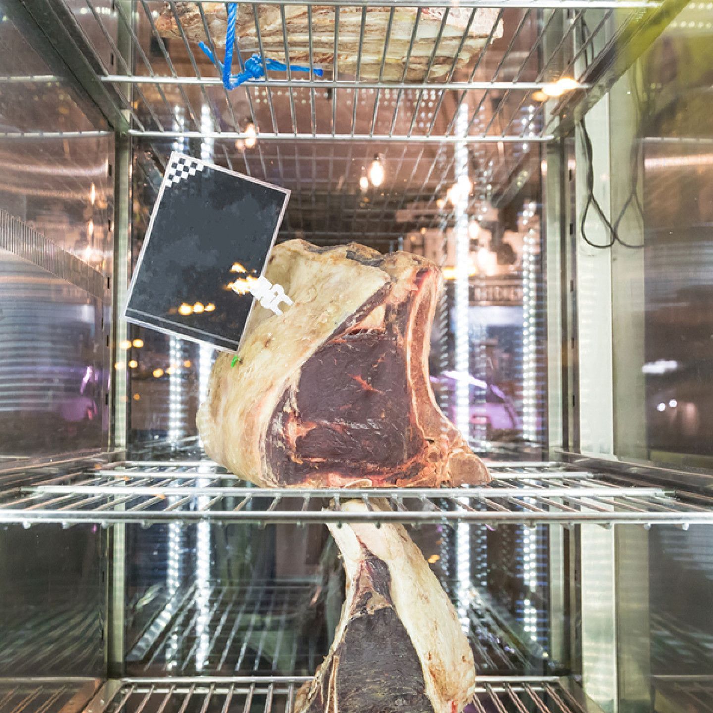 A large piece of meat is in a refrigerator with a price tag attached to it