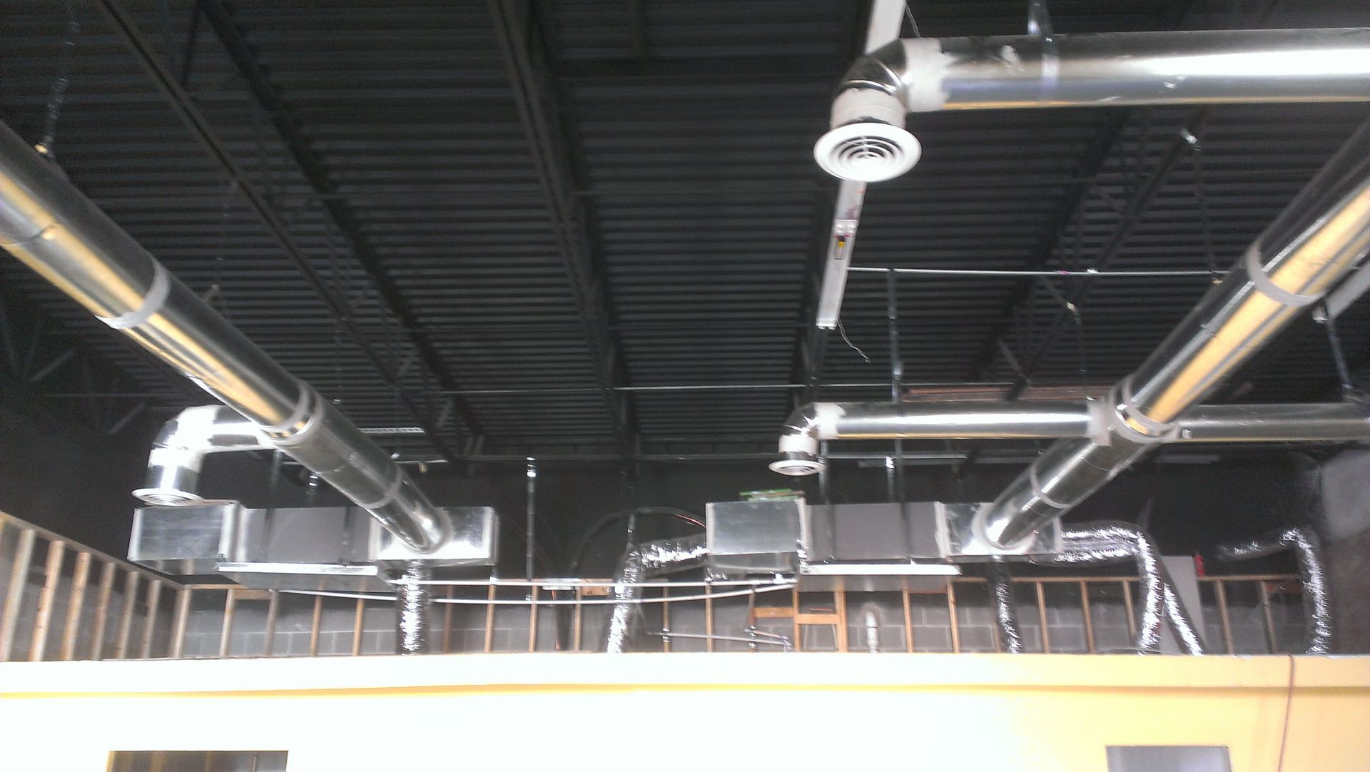A ceiling with a lot of air ducts hanging from it