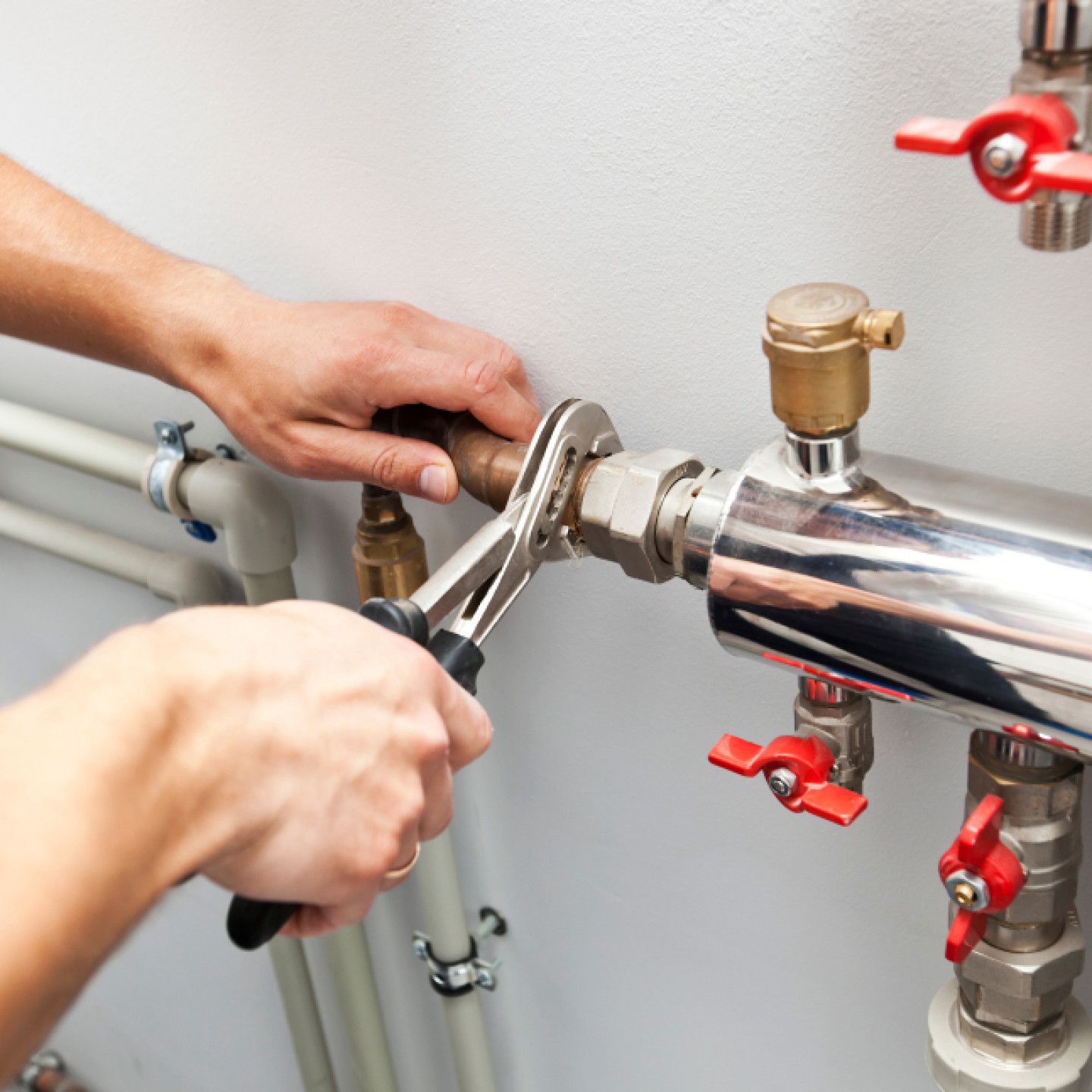 A person is fixing a pipe with a wrench