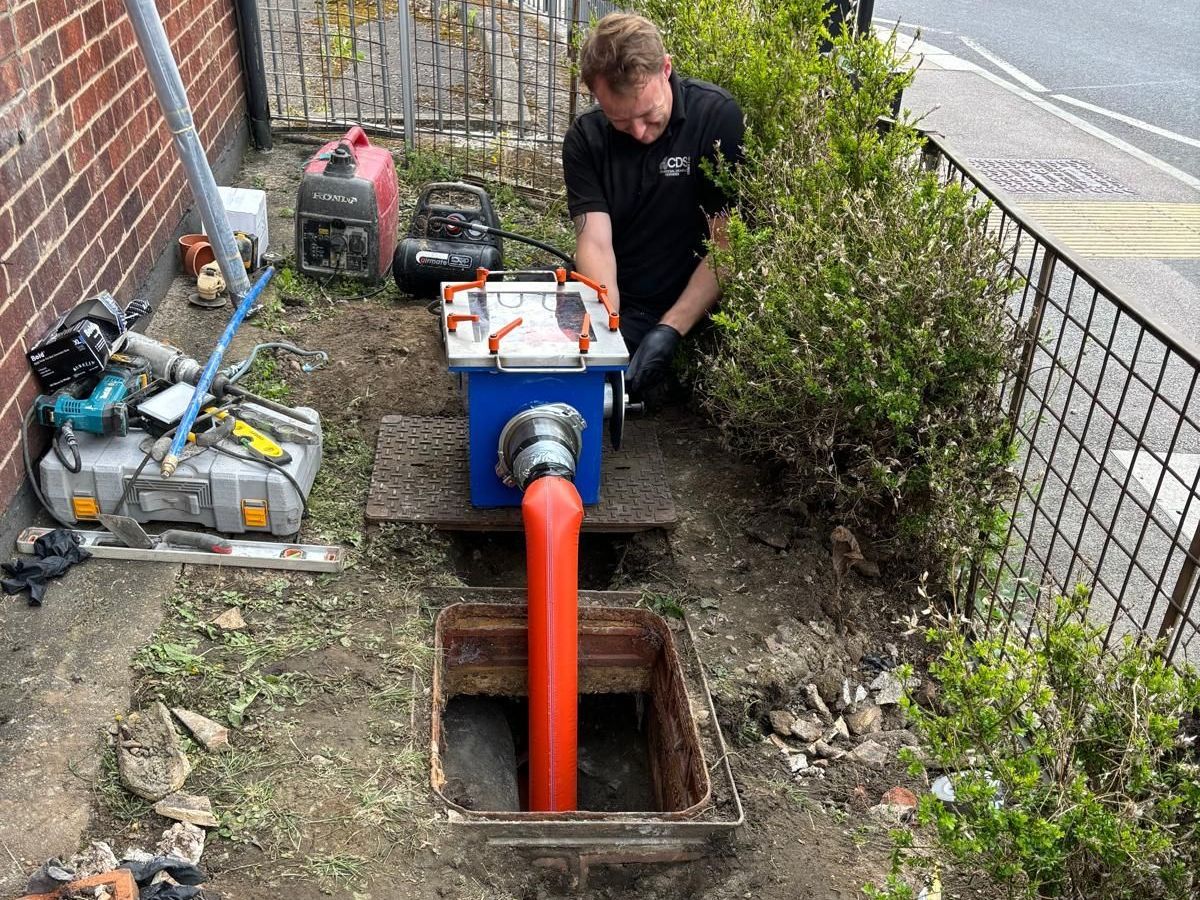 A CDS Ltd man is working on a drain in a garden.