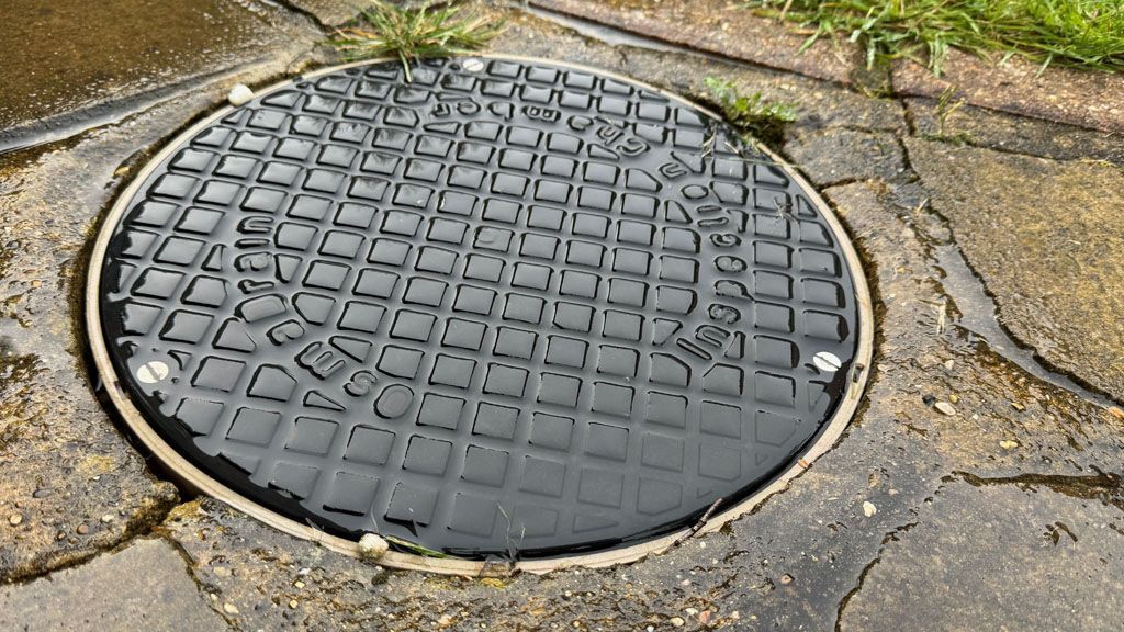 A manhole cover is sitting on the ground on a path.