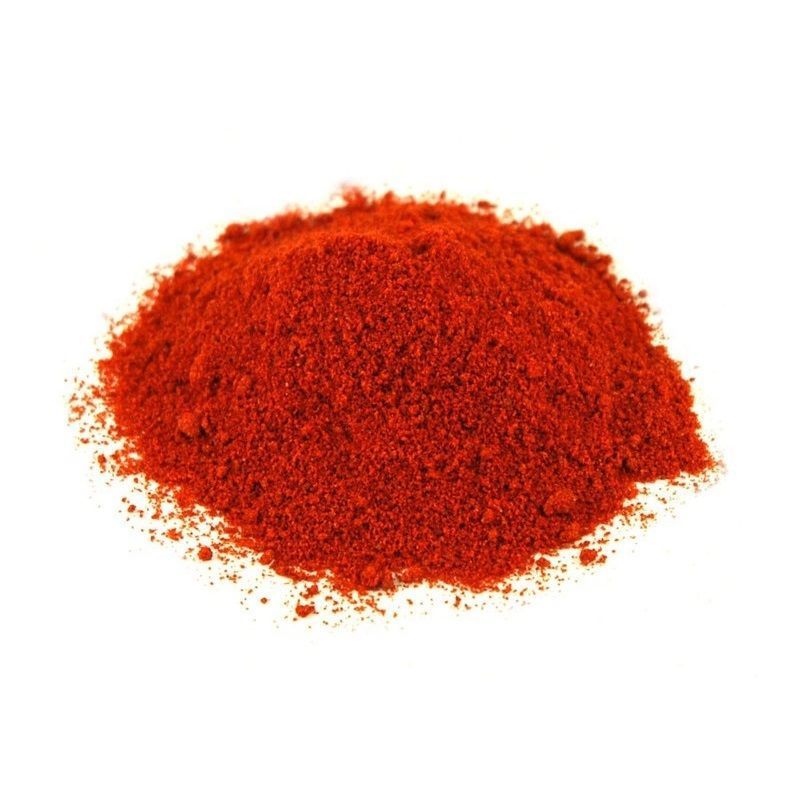 Montón de polvo de pimentón rojo brillante sobre una superficie blanca.