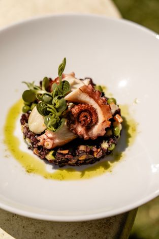 Rotoli di sushi impiattati con guarnizione e salsa su un piatto di ceramica decorato.