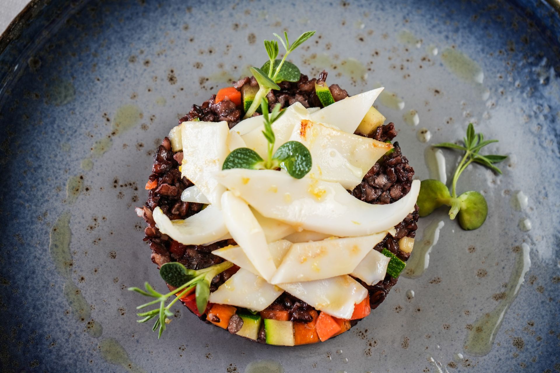 Antipasto di gamberi servito in una ciotola bianca con salsa ed erbe aromatiche, su un tavolo di ristorante.