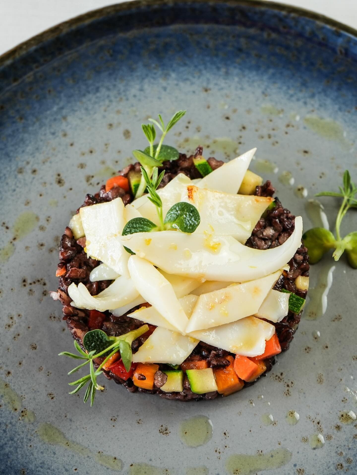 Insalata gourmet con formaggio grattugiato, cereali scuri e verdure in una ciotola grigio-blu.