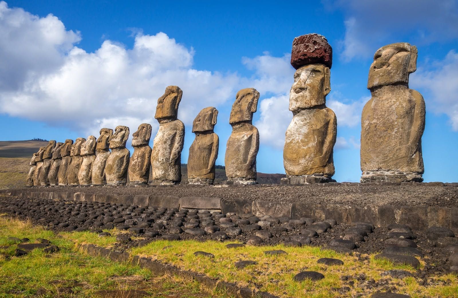 Row of Moai statues on Easter Island under a blue sky with clouds