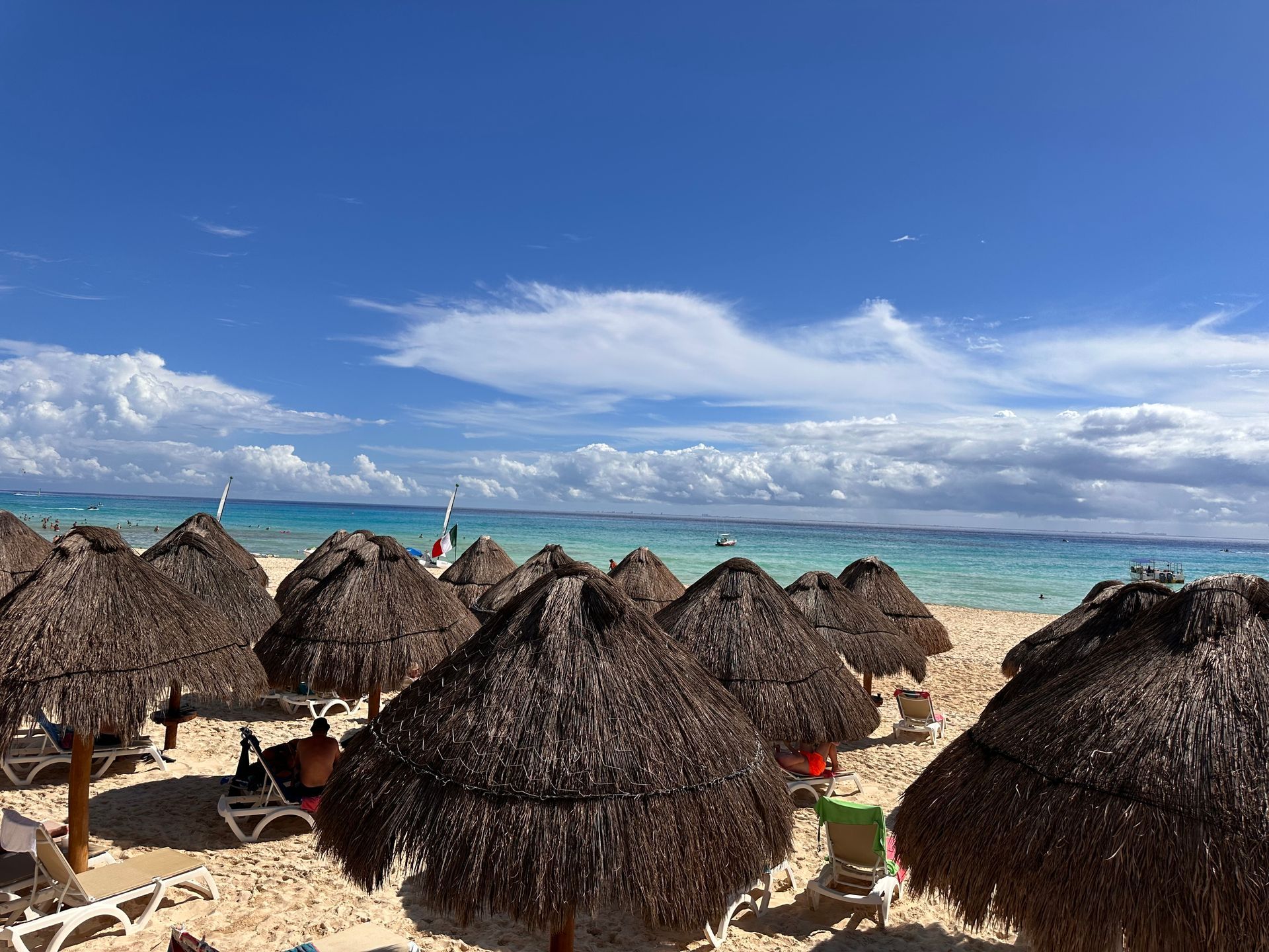 Thatched beach umbrellas on a sunny tropical shore with turquoise water and a blue sky