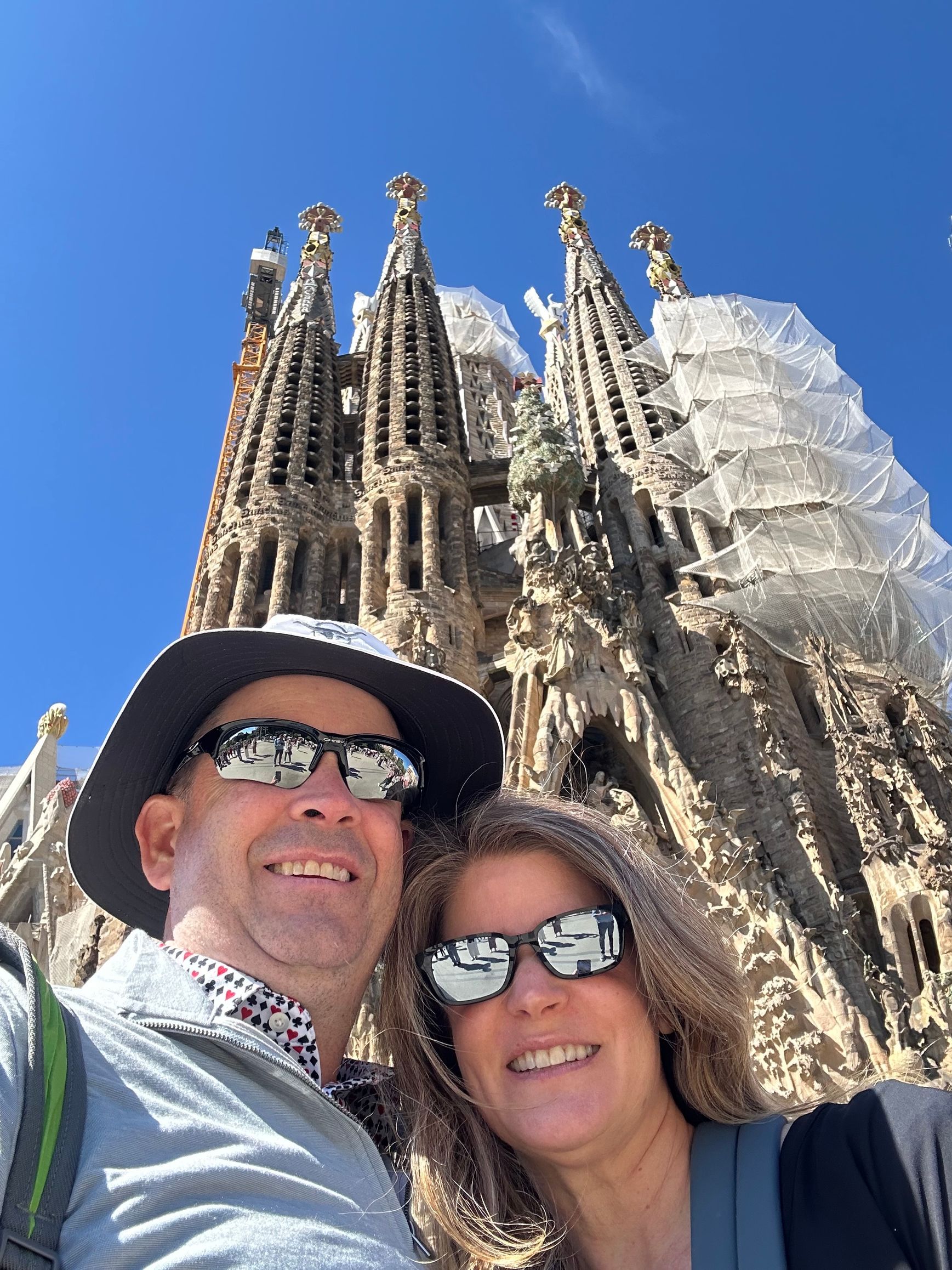 Couple taking a selfie in front of the Sagrada Família under a clear blue sky