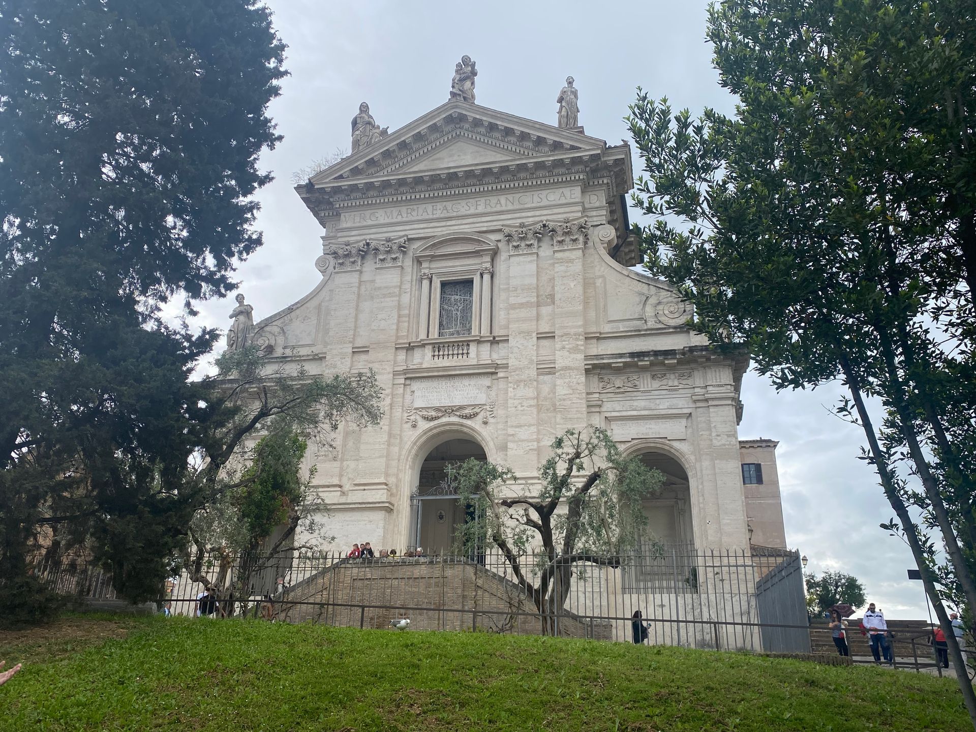 Historic stone church with ornate facade, framed by trees on a cloudy day