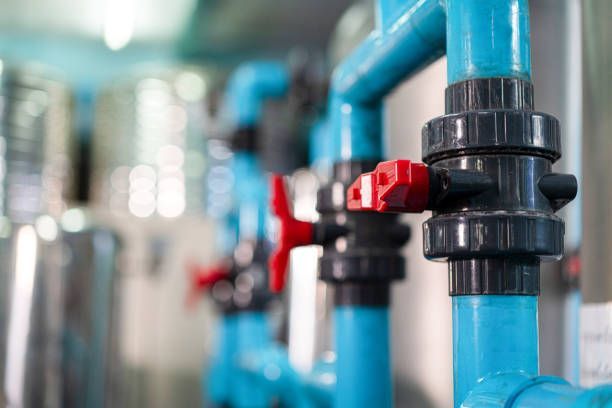 Blue pipes with red valves in a factory setting, partially out of focus.