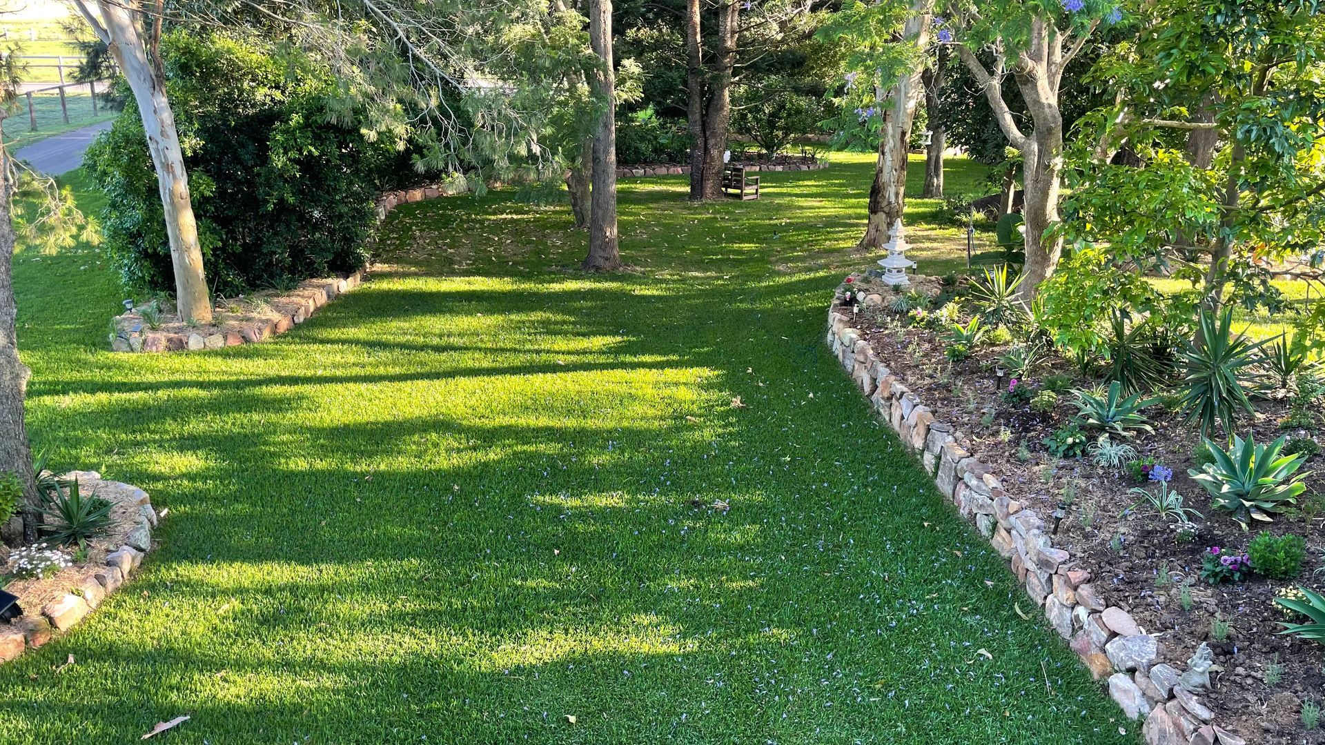 Sunlit garden path bordered by stone edging, with green grass — Edmonds Turf in Louth Park, NSW