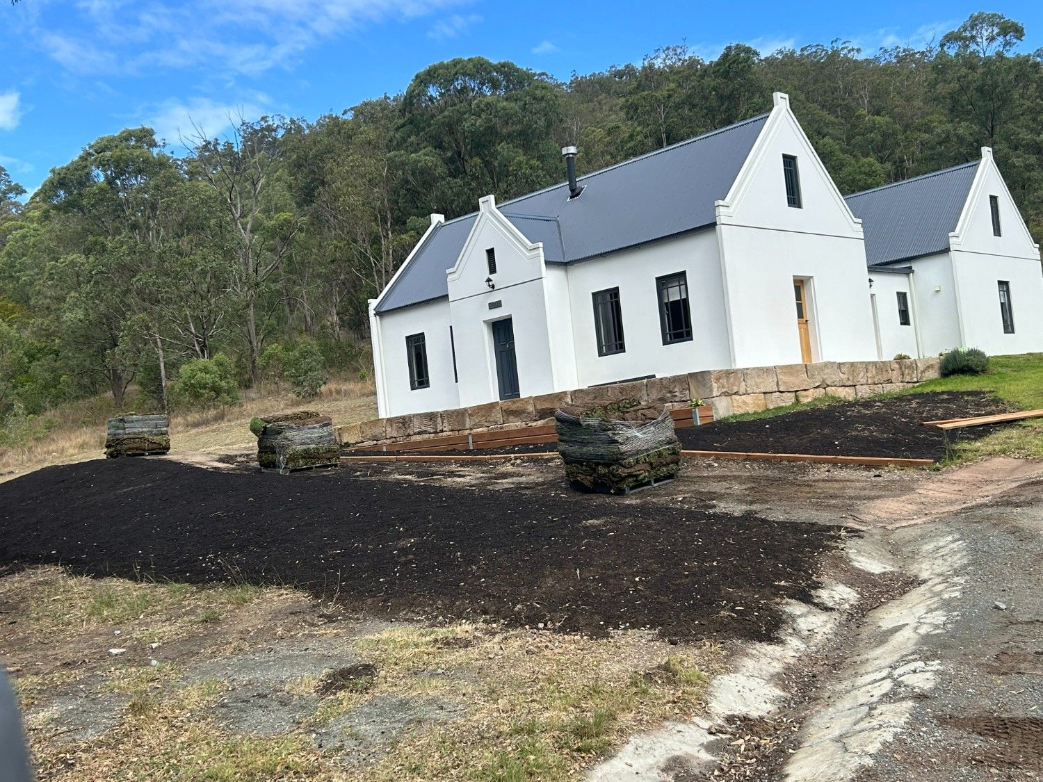 White House With Dark Roof on a Dirt Lot, Surrounded by Trees and Piles — Edmonds Turf in Louth Park, NSW
