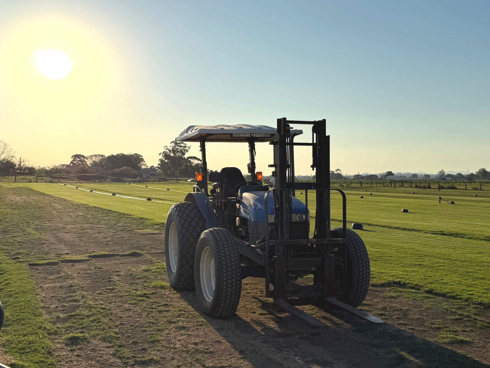 Two Workers in Green Workwear Install Fresh Grass Sod Strips on Prepared Soil — Edmonds Turf in Louth Park, NSW