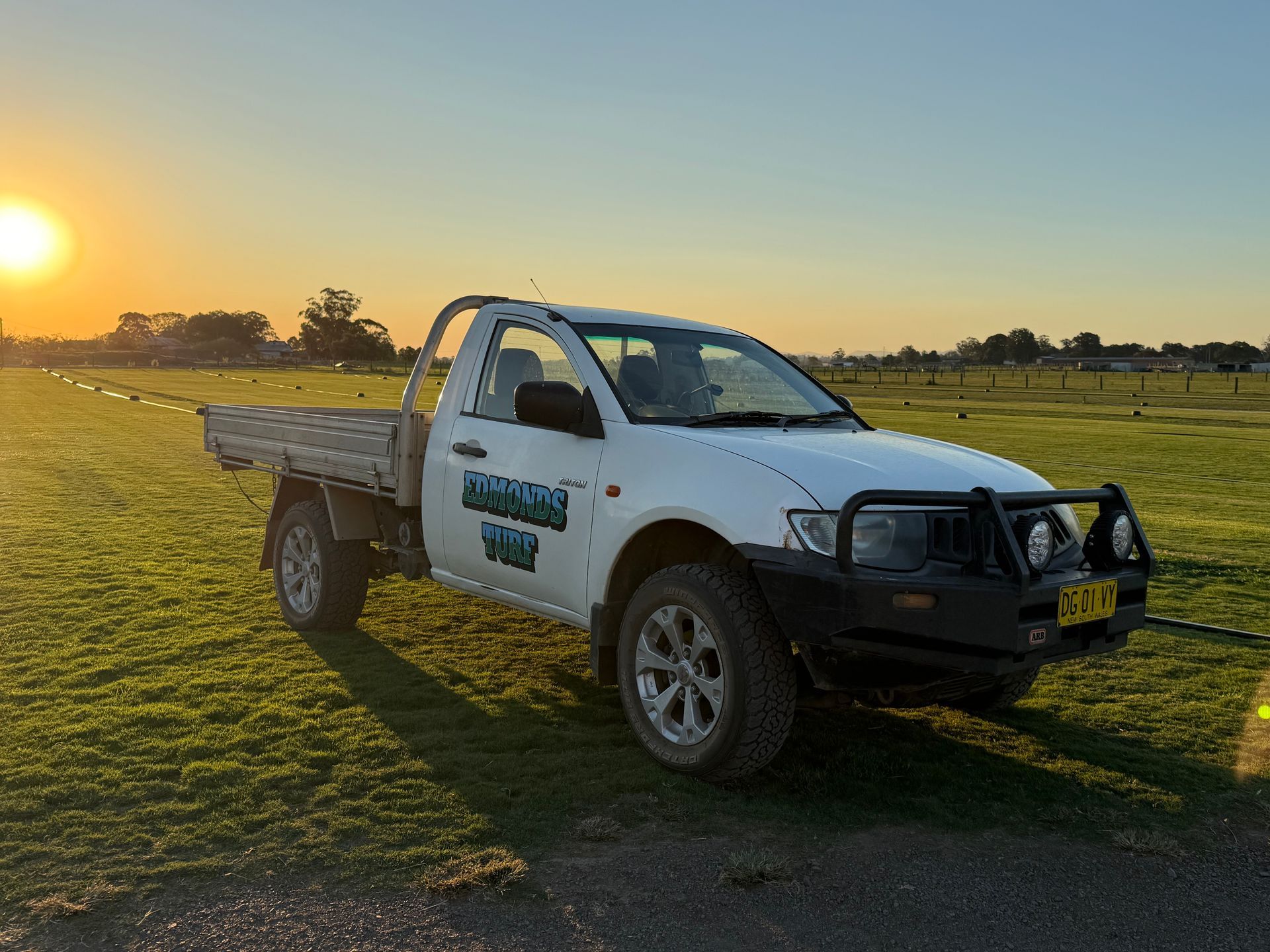 White Pickup Truck Parked on Grass at Sunset — Edmonds Turf in Newcastle, NSW