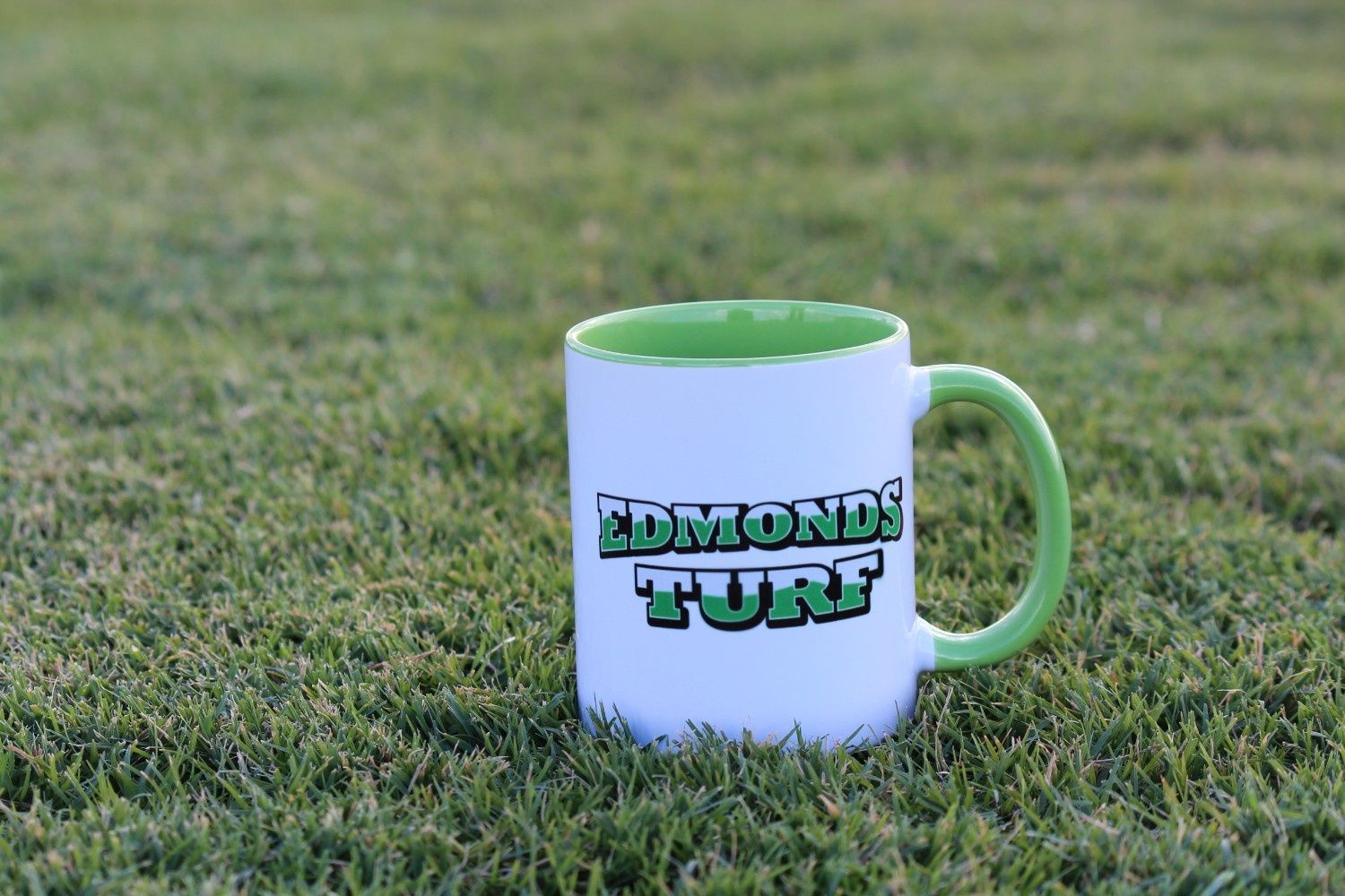 White Mug With Green Handle and Interior on Grass — Edmonds Turf in Louth Park, NSW