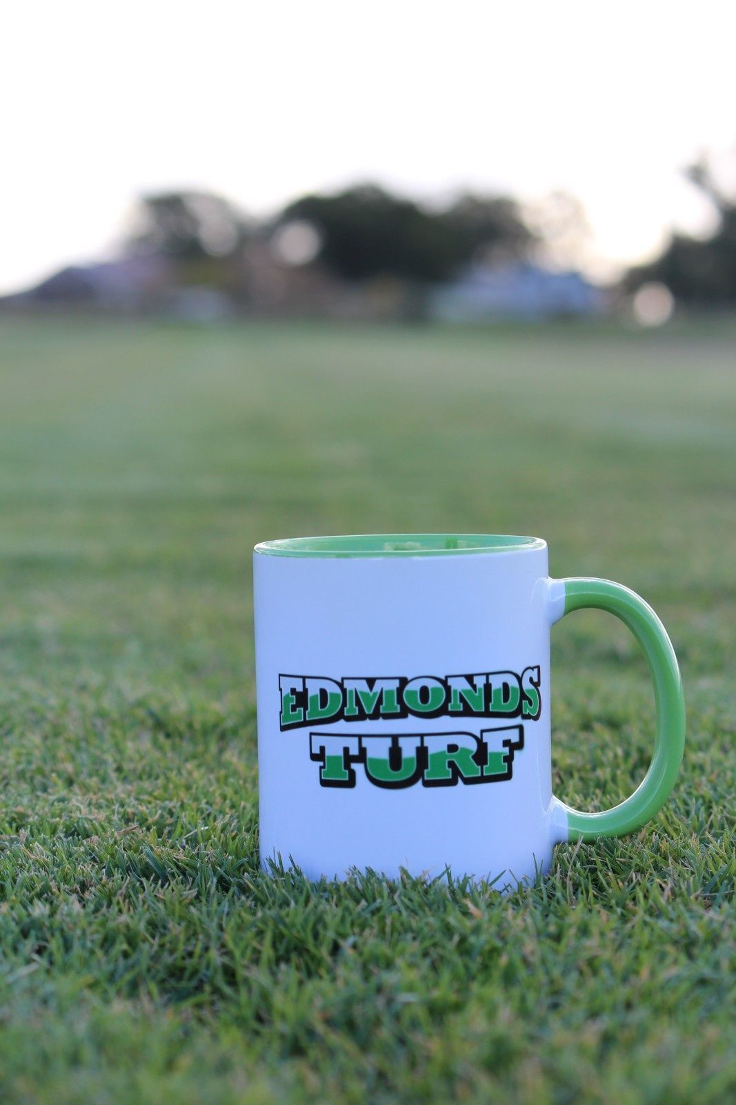 White Mug With Green Handle Sitting on Grass — Edmonds Turf in Louth Park, NSW