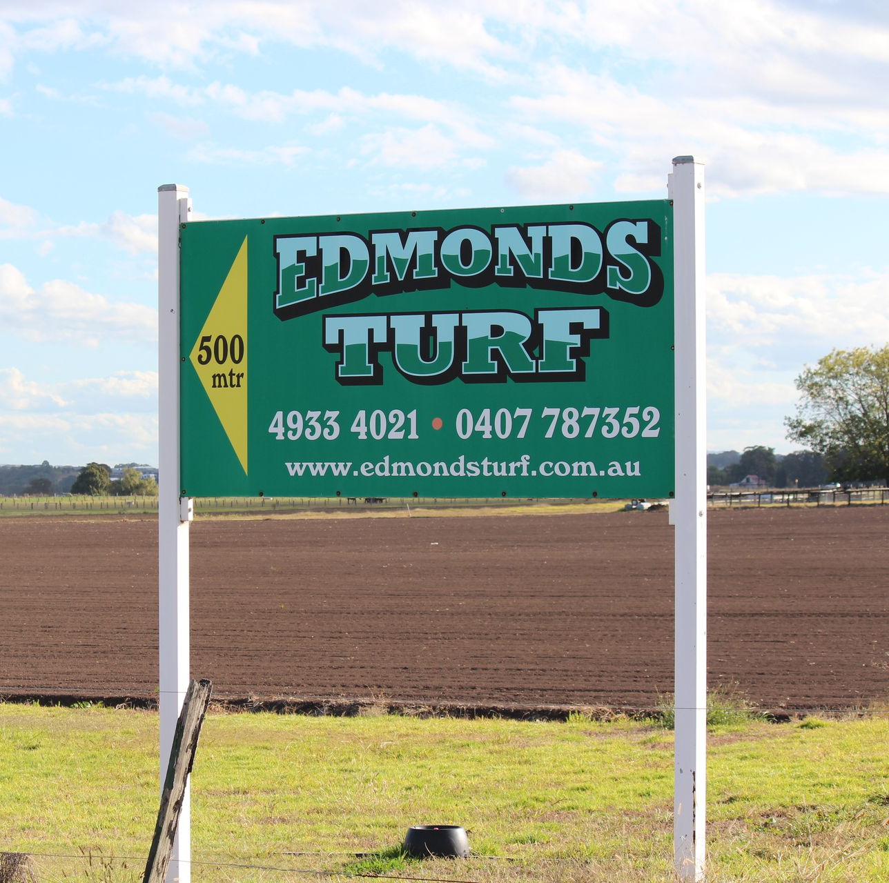 Edmonds Turf roadside sign in a field, green with white posts and contact details.