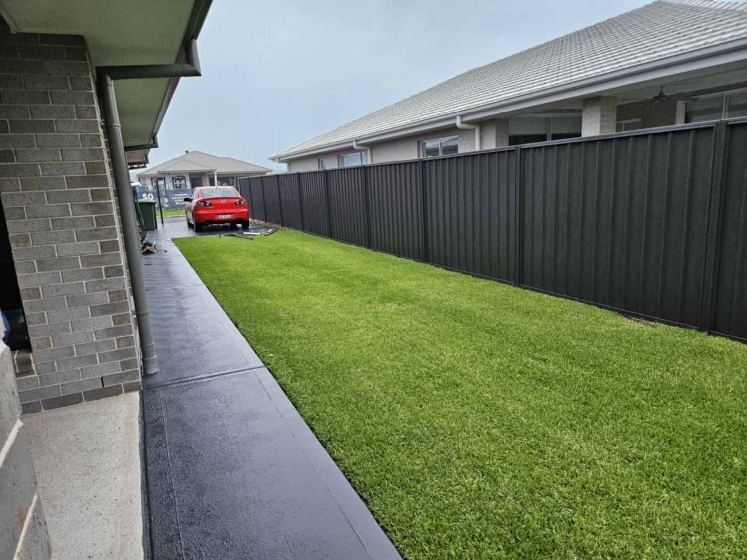 Narrow Side Yard With Green Lawn, Dark Fence — Edmonds Turf in Louth Park, NSW