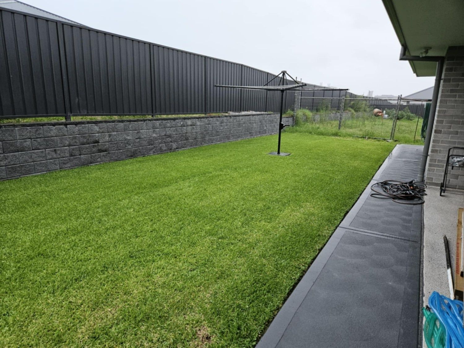 Backyard With Green Lawn, Stone Retaining Wall — Edmonds Turf in Louth Park, NSW