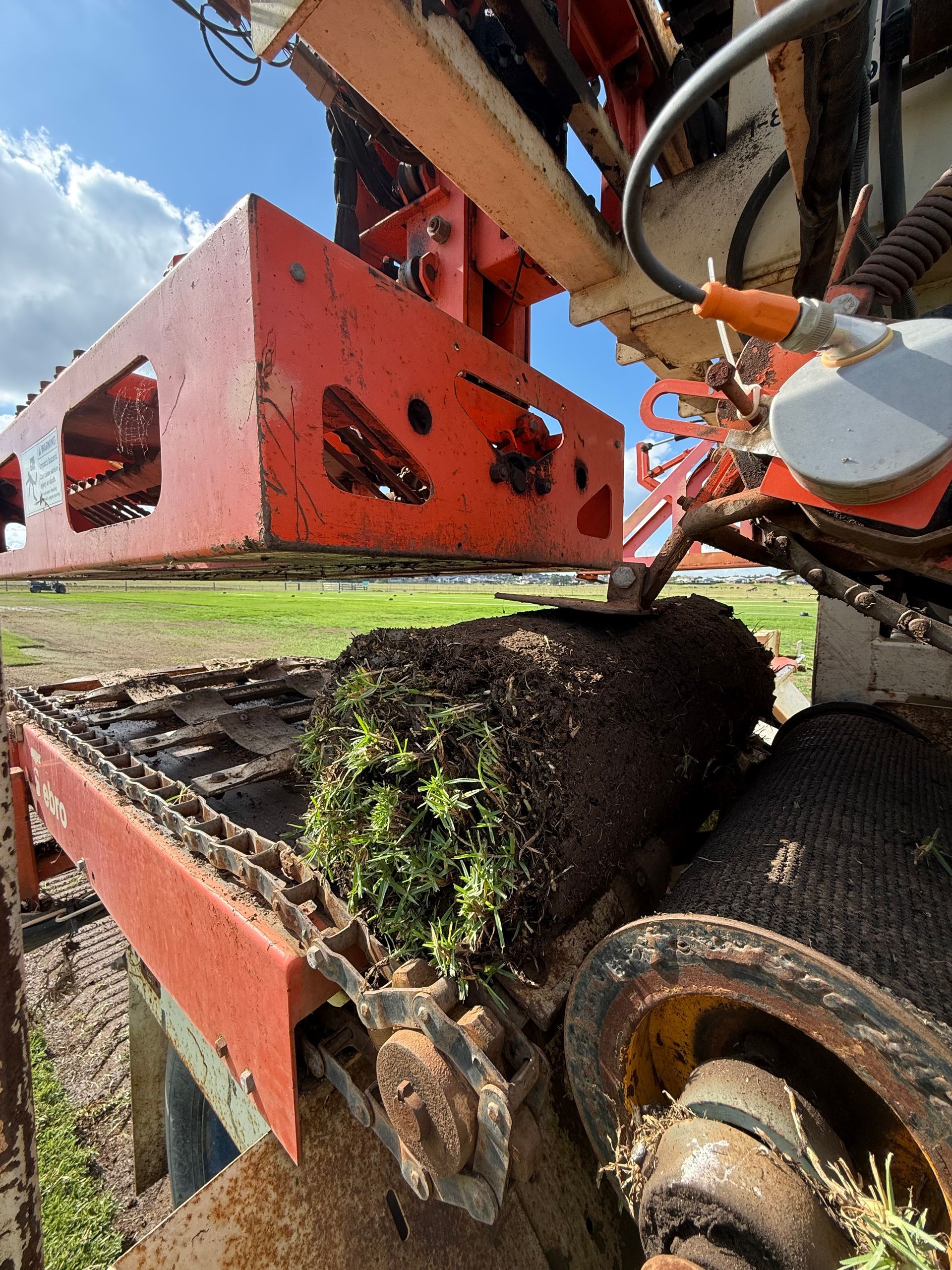 Rusty Farm Machinery Cutting Moss-Covered Turf Under a Blue Sky — Edmonds Turf in Louth Park, NSW