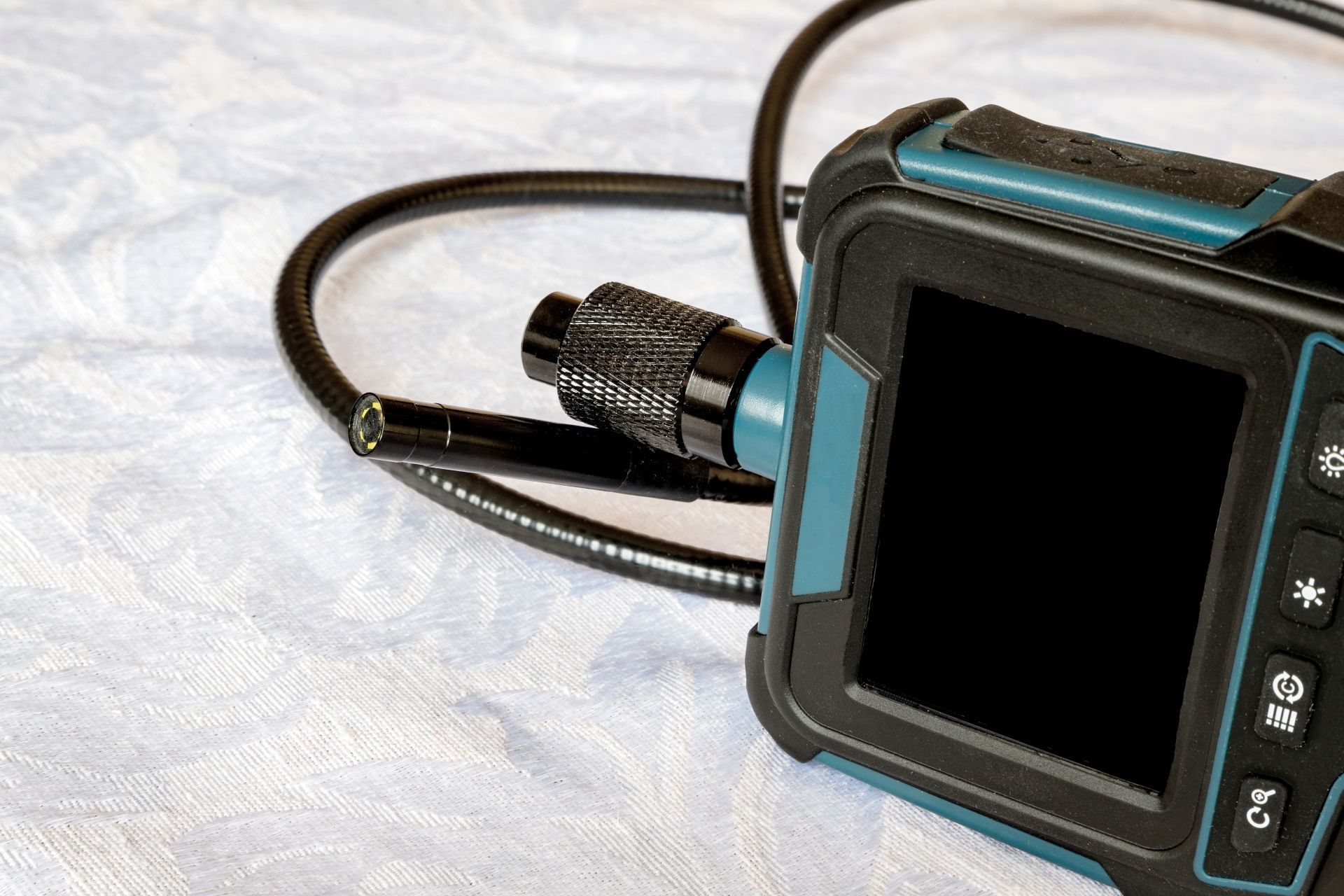 A handheld industrial borescope inspection camera with a flexible black probe attached to a blue and black display unit.