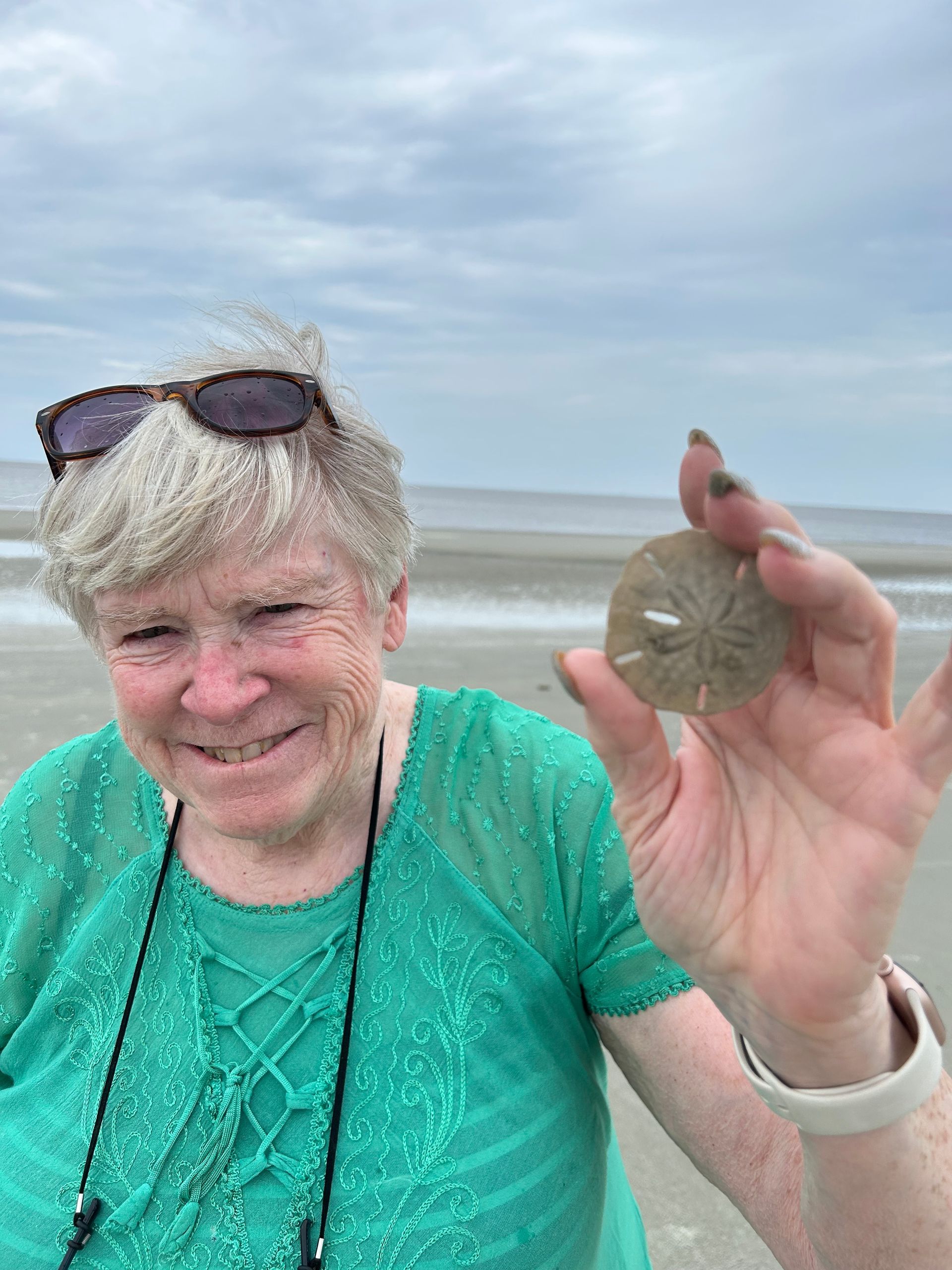 Picture of Nancy Klapak on beach holding sand dollar
