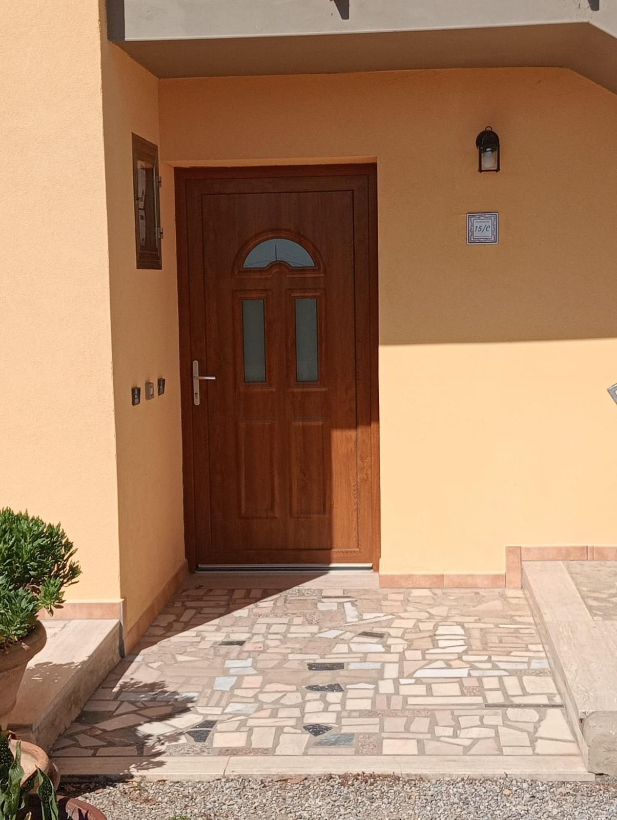 Porta di legno marrone in un corridoio, con un termosifone e oggetti incorniciati alle pareti.