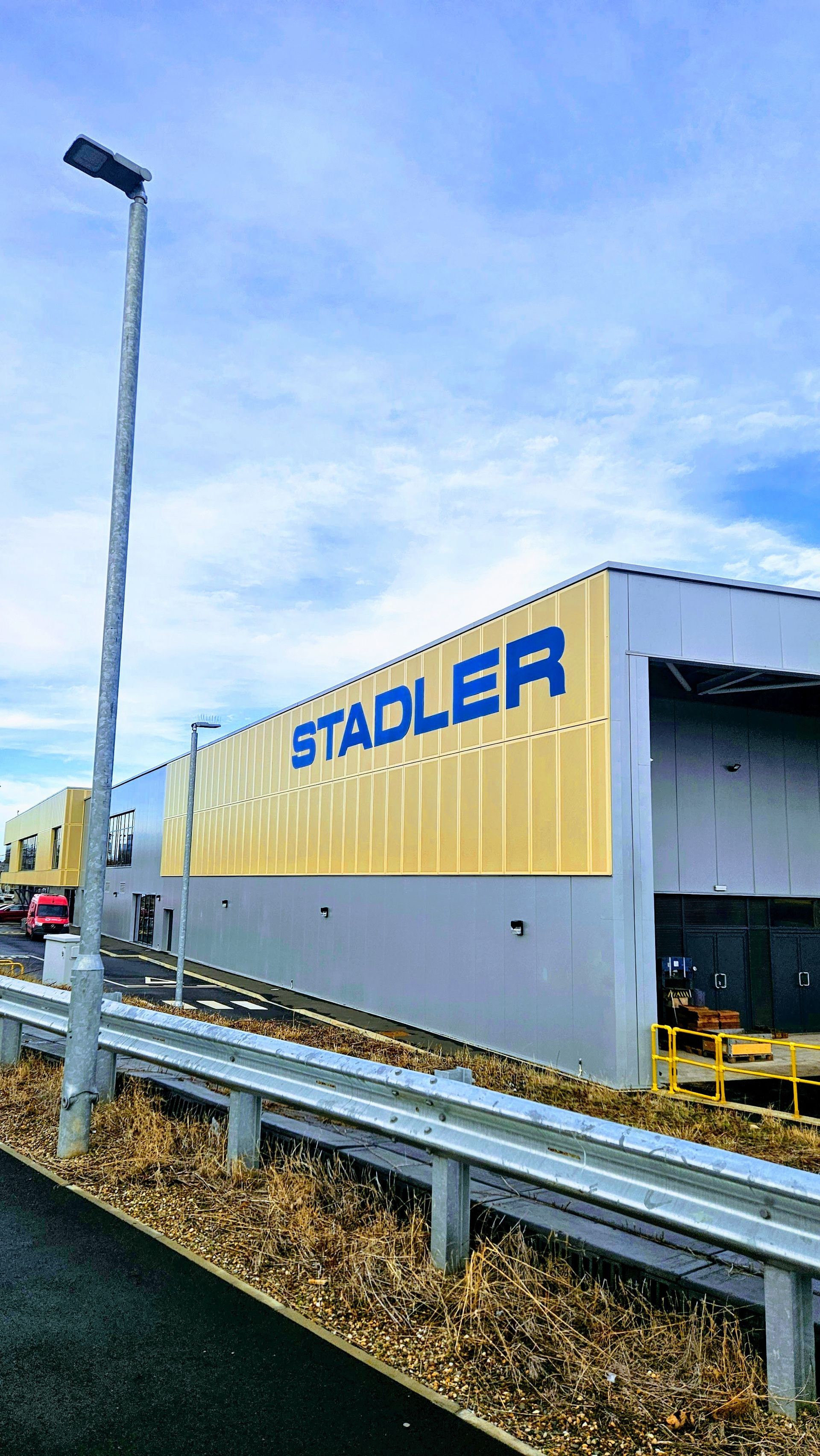 STADLER building exterior with sign on yellow and gray wall, under blue sky.