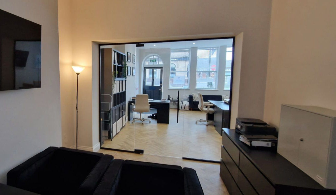 Glass office partition with frameless glass door and black hardware