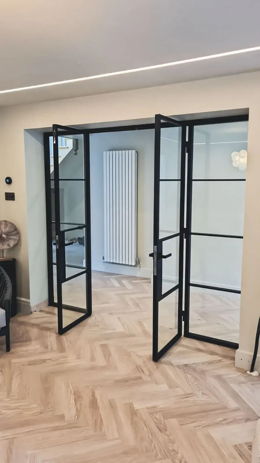 Bespoke black steel glass doors with side panels and industrial-style bars installed in a residential home