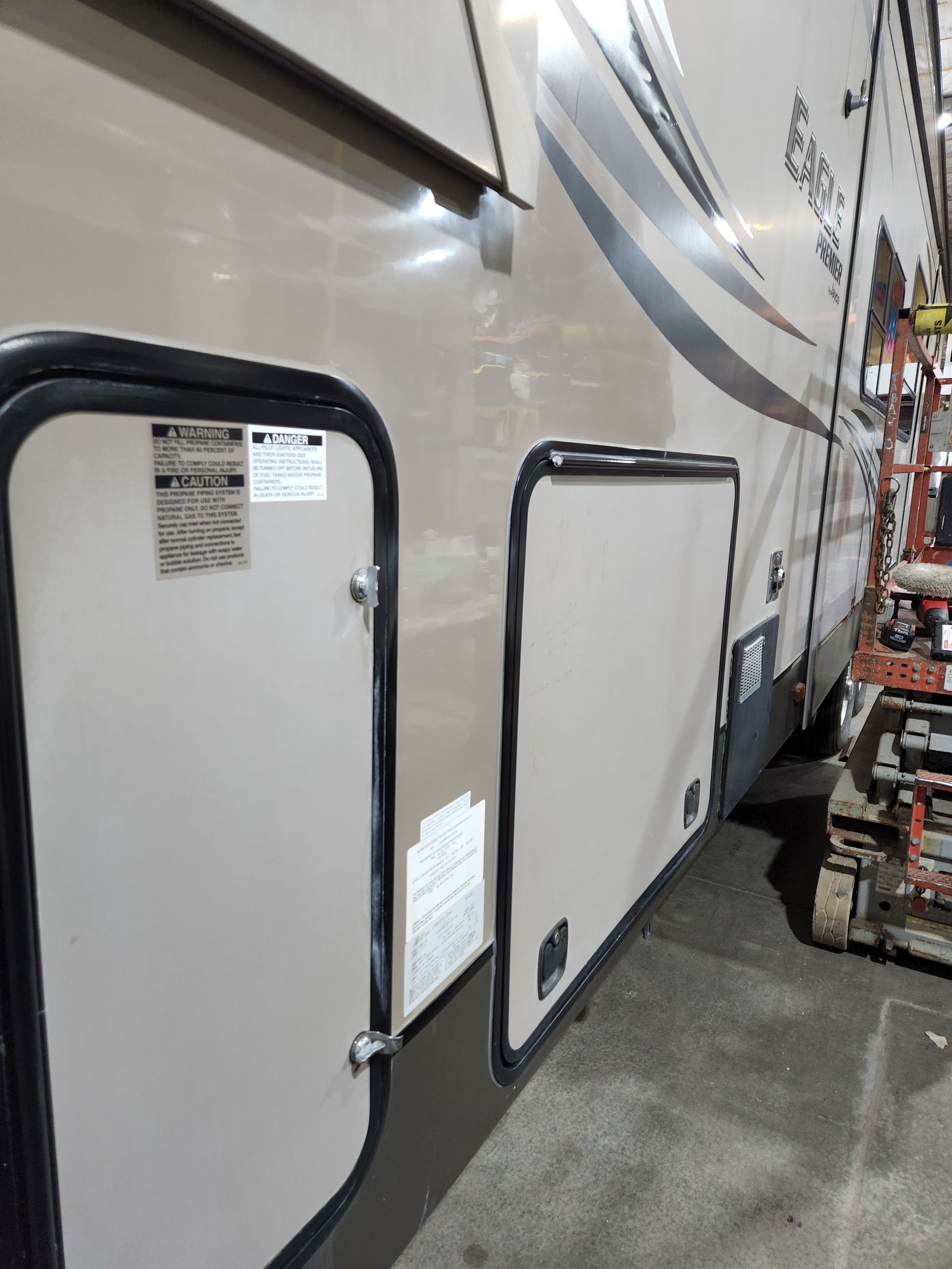 White trailer side with two black-framed access hatches in a warehouse aisle