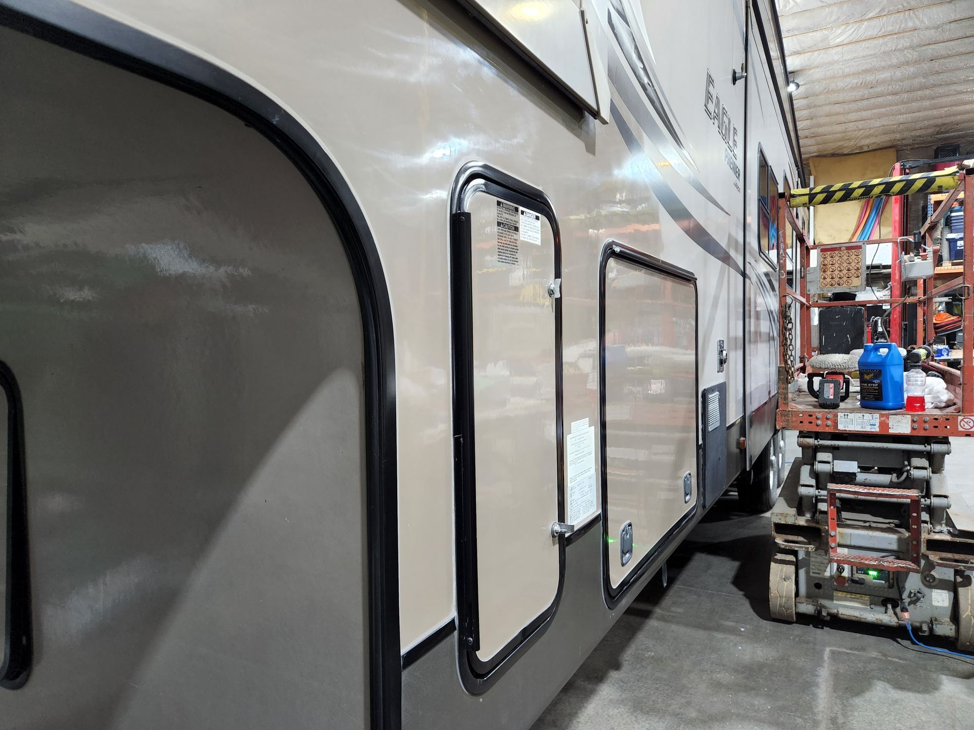 White RV in a service bay with a lift and tools nearby
