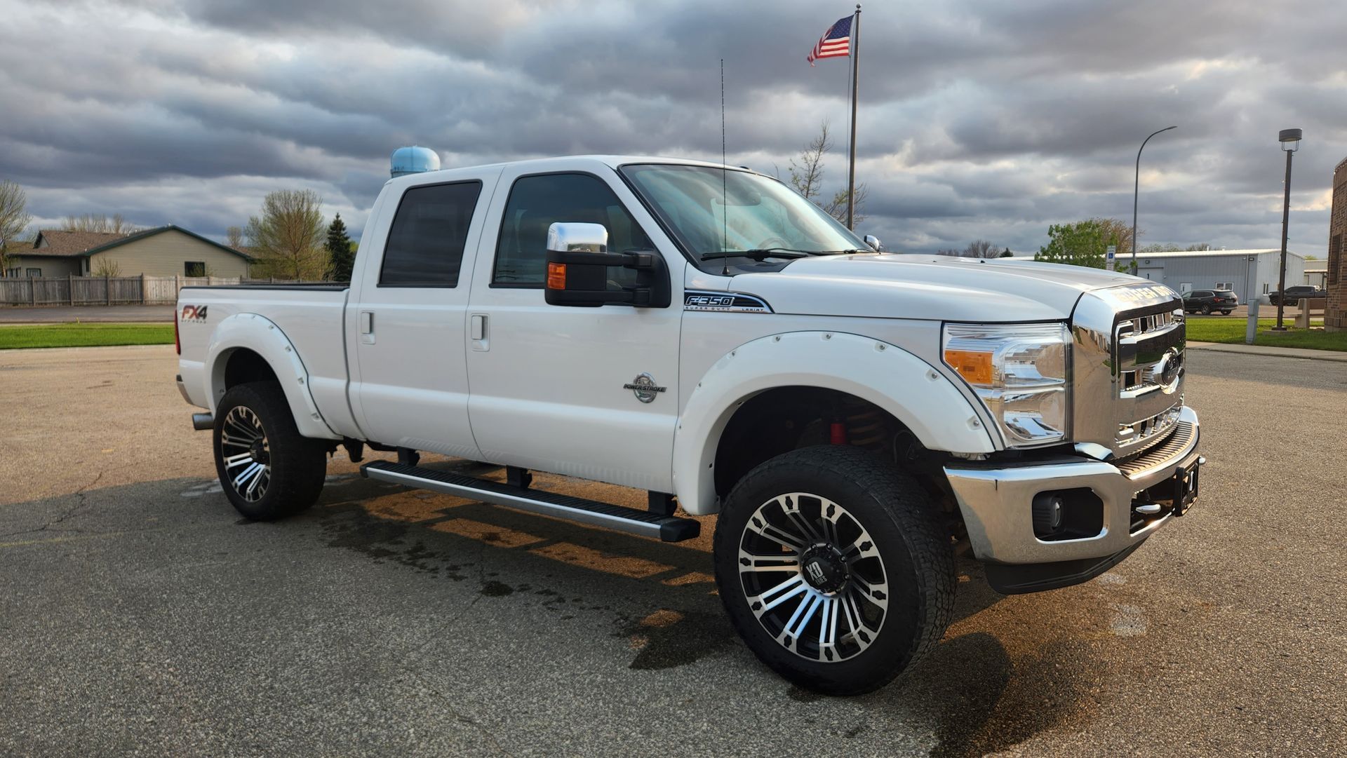 White lifted Ford pickup truck parked outdoors under cloudy sky at a dealership lot
