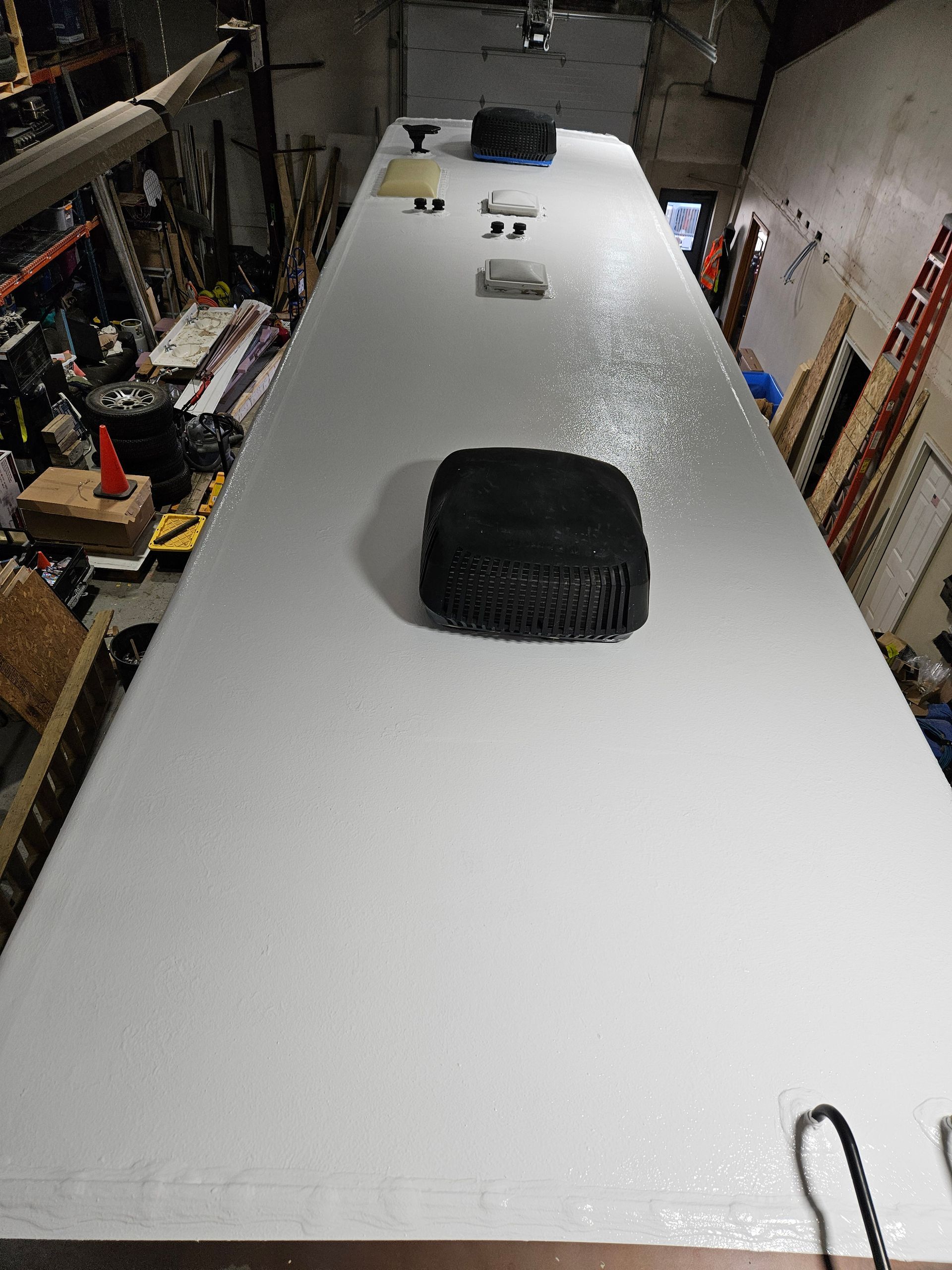Long white tabletop in a workshop, with tools and small items near the far end and a black bag in the foreground