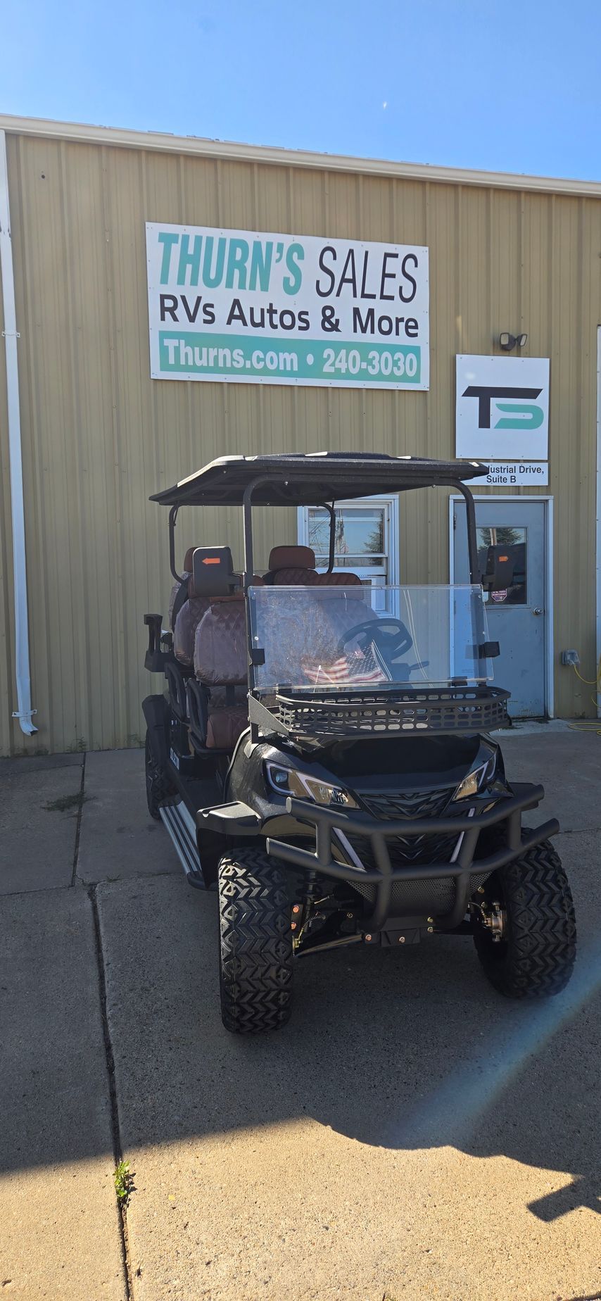 Black golf cart parked outside a Thurn’s Sales building with a sign and vending machine