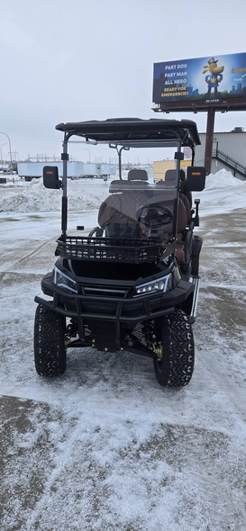 Black off-road utility cart parked on snowy ground with a billboard in the background.