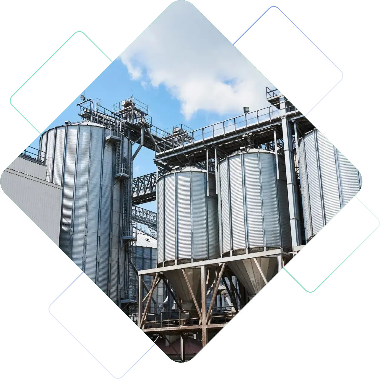 Silos industriais e passarelas metálicas sob um céu azul parcialmente nublado.