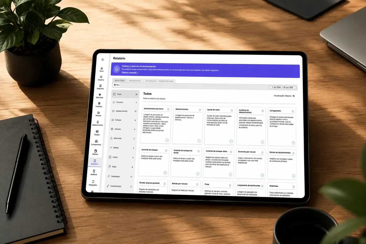 Tablet exibindo um aplicativo de painel branco sobre uma mesa de madeira ao lado de um caderno e uma planta.