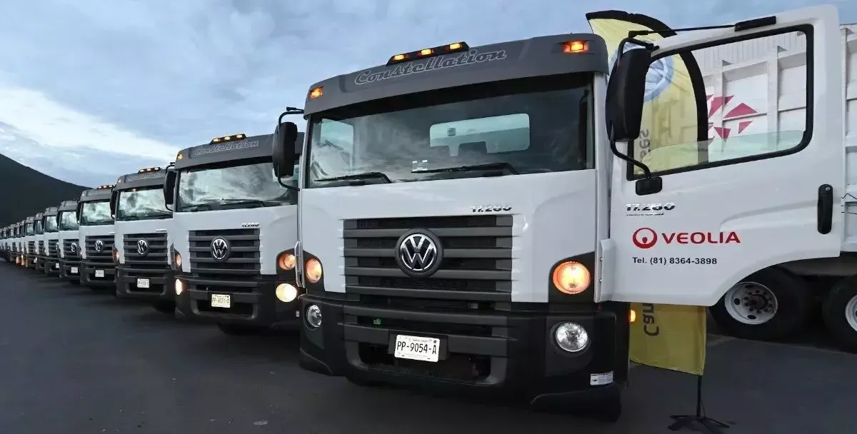 Fileira de caminhões brancos  ao ar livre; a porta do caminhão está aberta, com o logo da Veolia