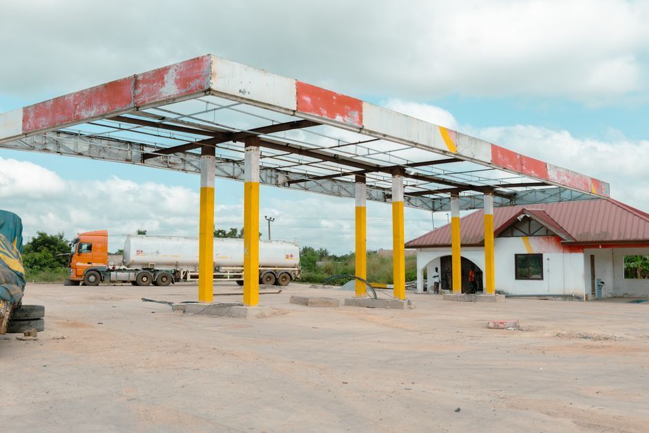 Caminhões estacionados em pátio ao lado de bomba e tanque de diesel para abastecimento interno.