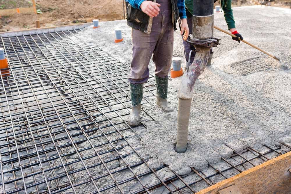 Man Pouring Concrete into Foundation — NBM Constructions