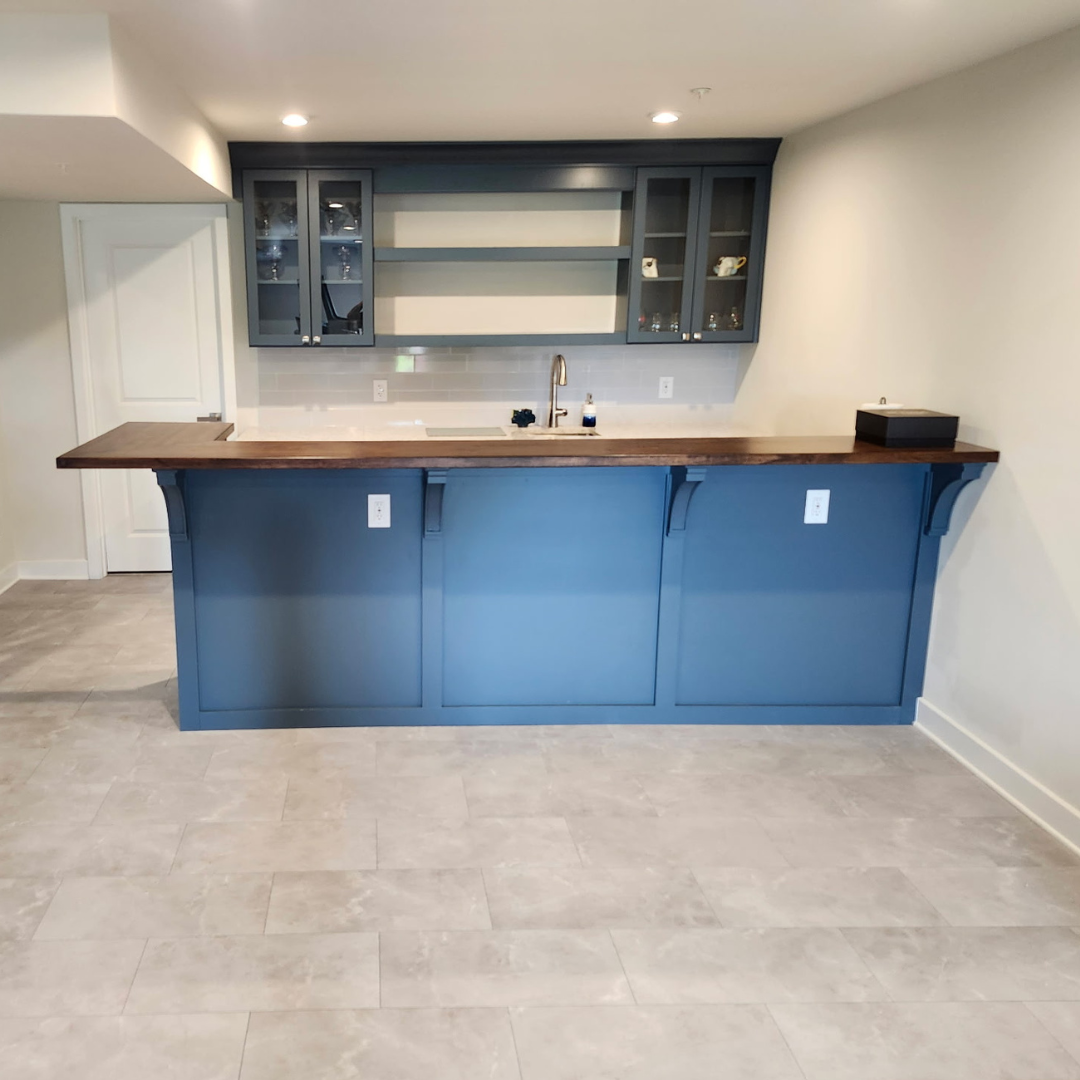 Bright blue home bar with wood countertop and gray cabinets in a tiled room
