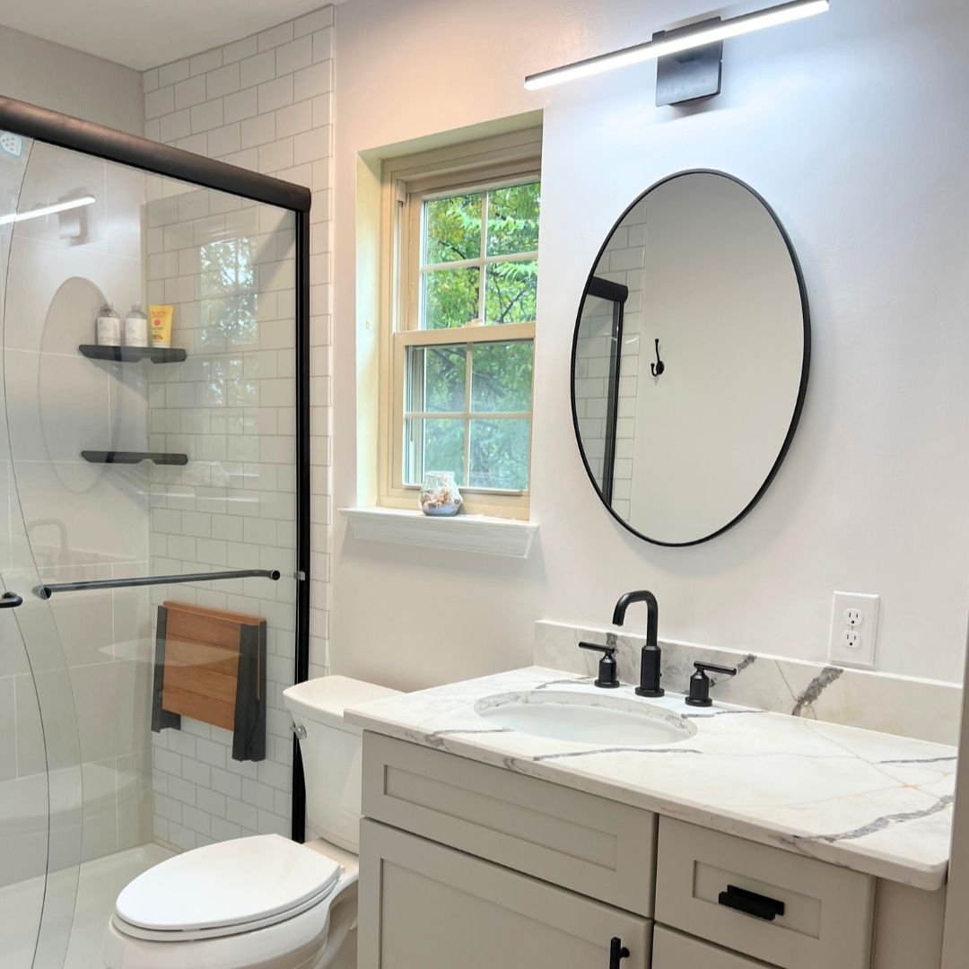 Bathroom Remodel with Marbled Countertop plus Vanity and Mirror with Light Behind It.