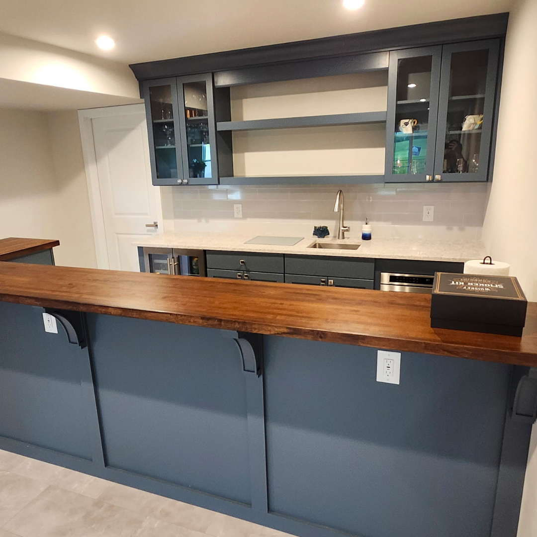 Modern kitchen with blue-gray cabinets, wood island, and open shelving under bright lights